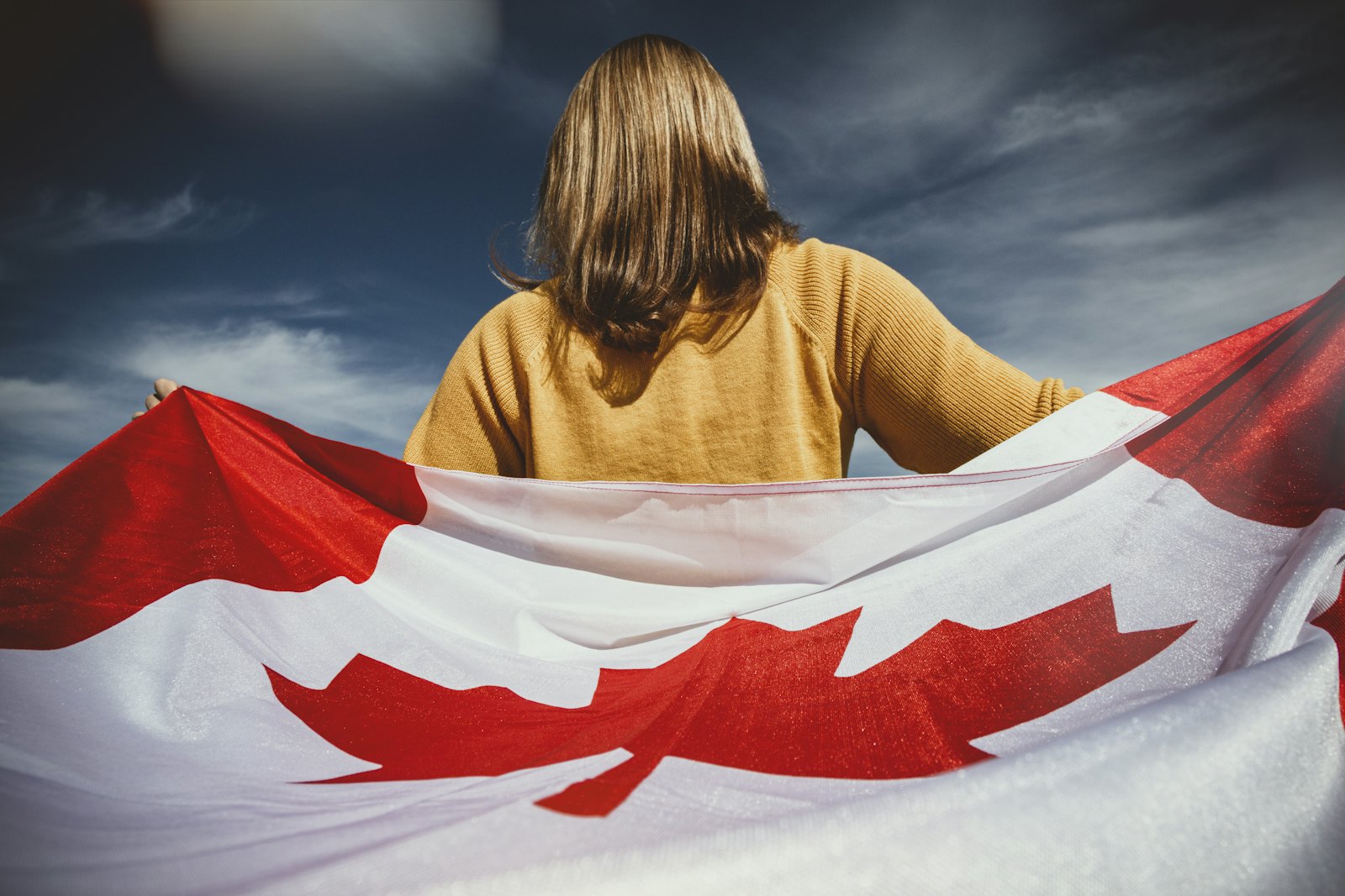 手持加拿大国旗的女性，象征华人移民加入加拿大大家庭
